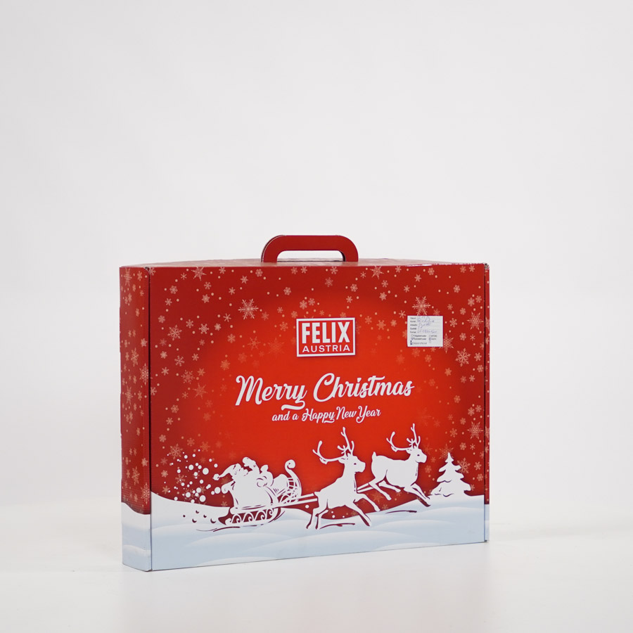 Rote Weihnachtsverpackung im Kofferstill mit Henkel mit Aufdruck „Merry Christmas and a Happy New Year“ und Motiv von Santa Claus im Schlitten mit Rentieren – Promotionkoffer von Felix Austria, produziert von Bauernfeind Druck + Display.